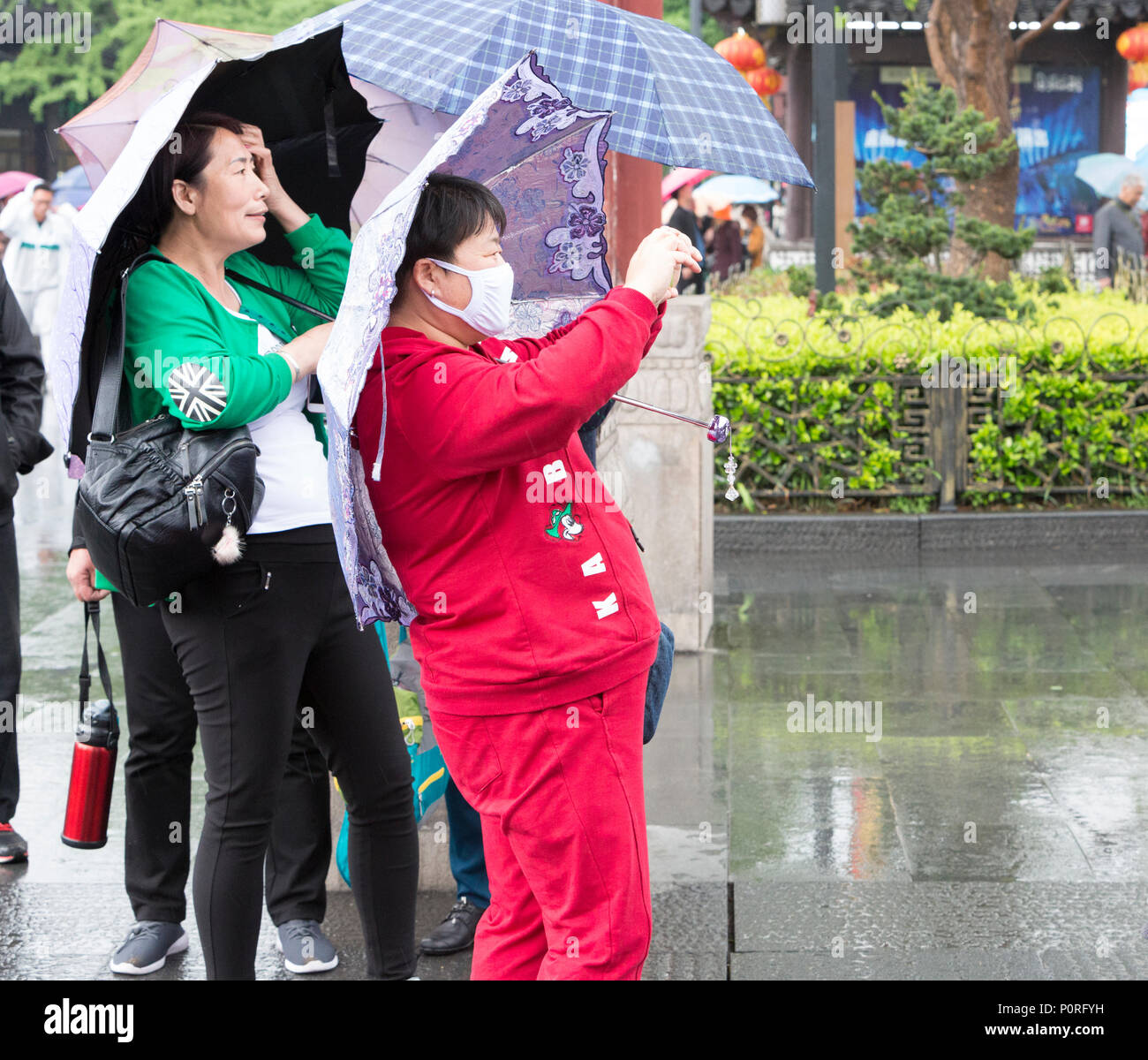 Nanjing, Jiangsu, Cina. Donna con una maschera per la respirazione di scattare una foto con il suo telefono cellulare. Foto Stock