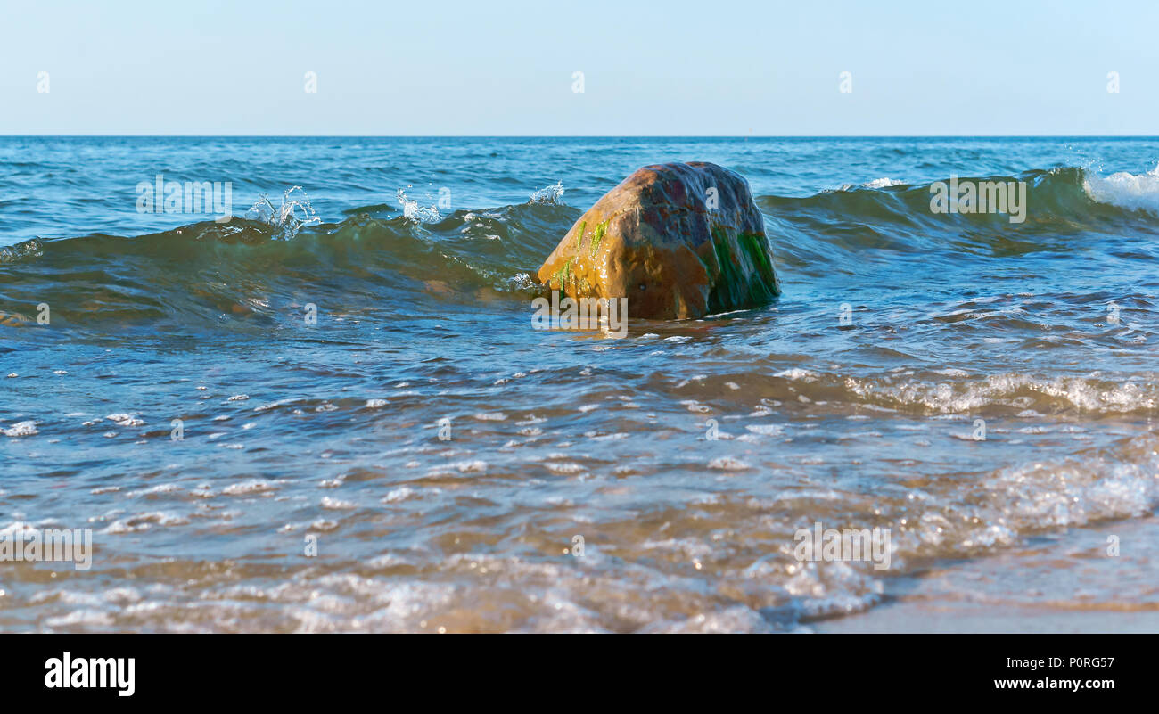 Le onde del mare sono battendo sulle rocce sulla riva, l'onda si rompe su  una roccia Foto stock - Alamy