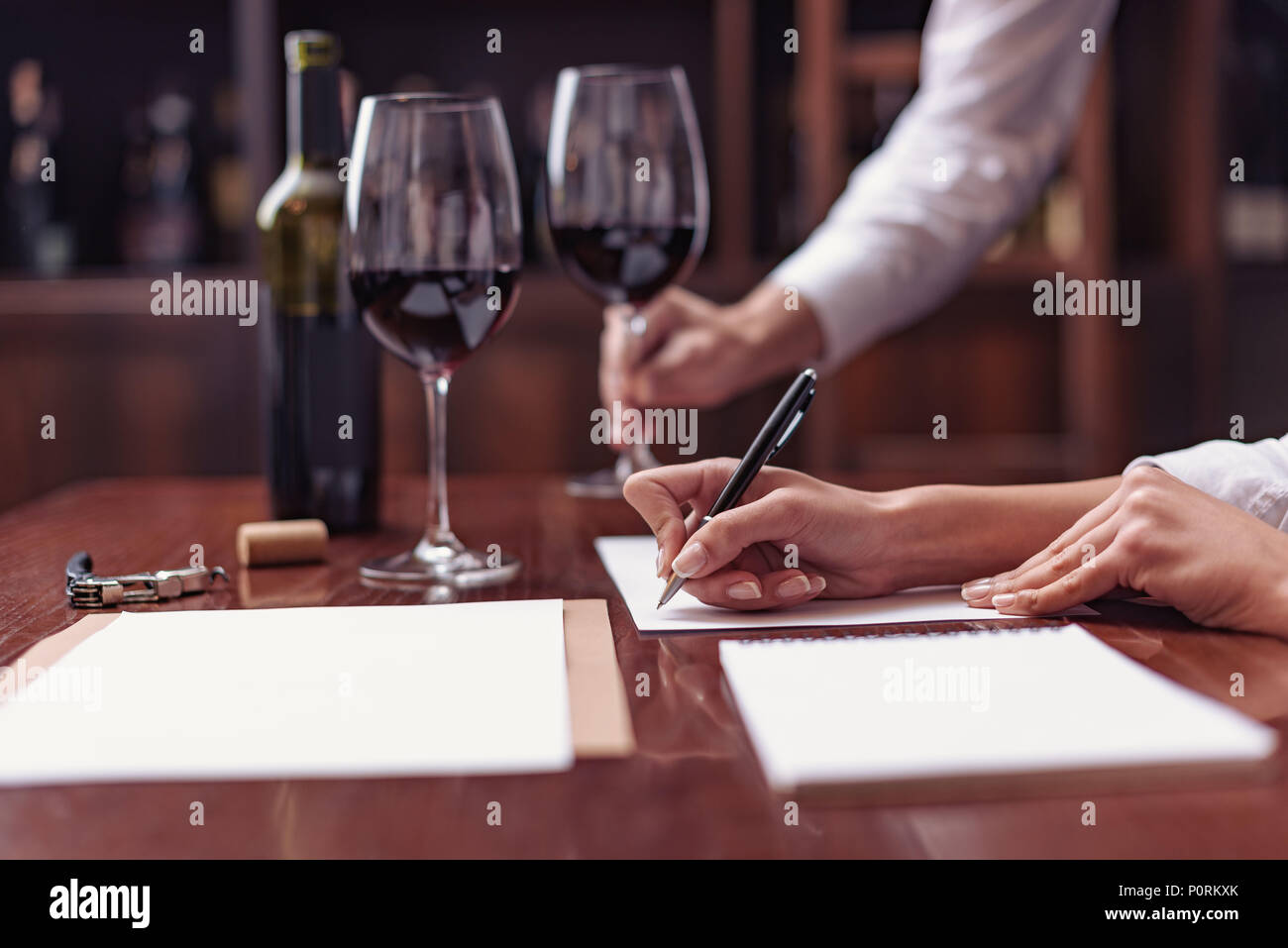 Due sommeliers, maschio e femmina di degustazione di vino rosso e rendere note alla scheda di degustazione Foto Stock