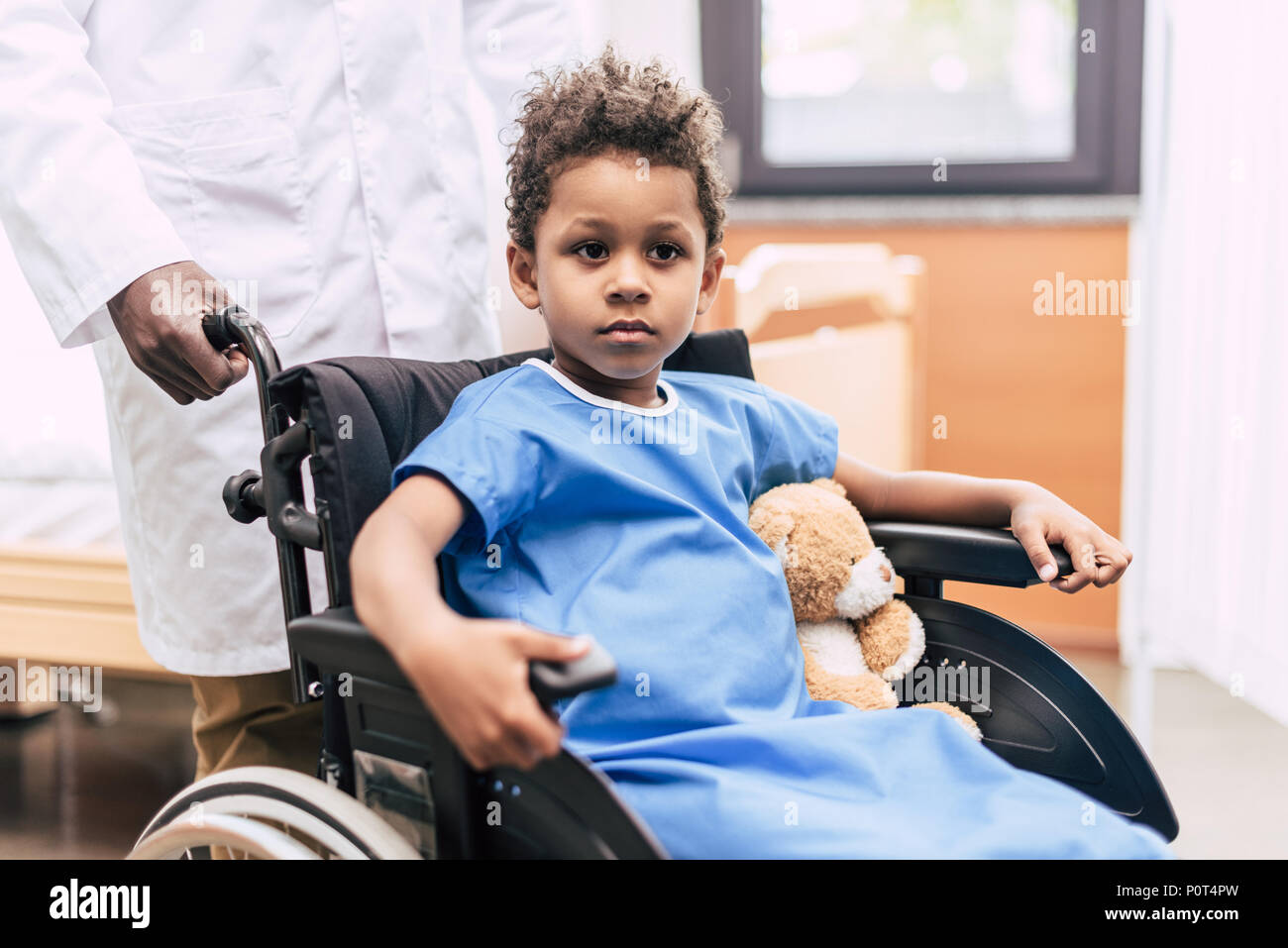 Ritratto di pensieroso African American Boy in sedia a rotelle che guarda lontano in ospedale Foto Stock