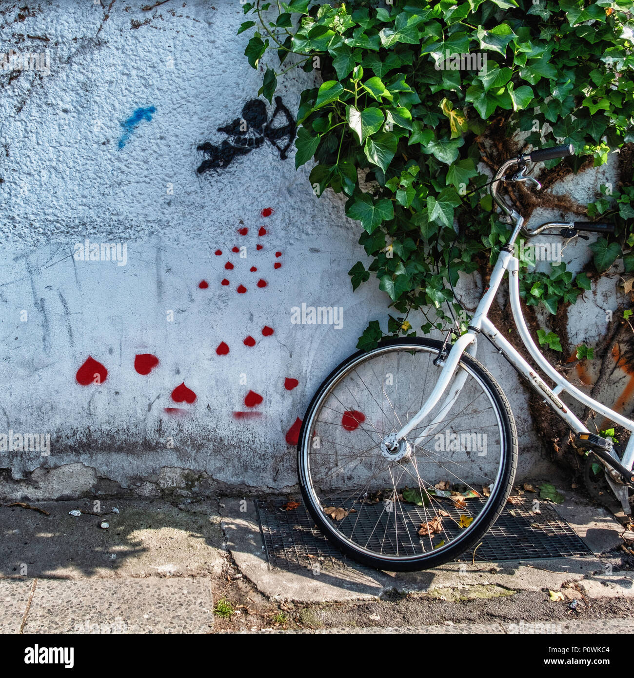 Berlin Mitte. Urban Still Life, Arte di strada, Amorino con cuori rossi sulla coperta di edera e di parete di biciclette parcheggiate Foto Stock