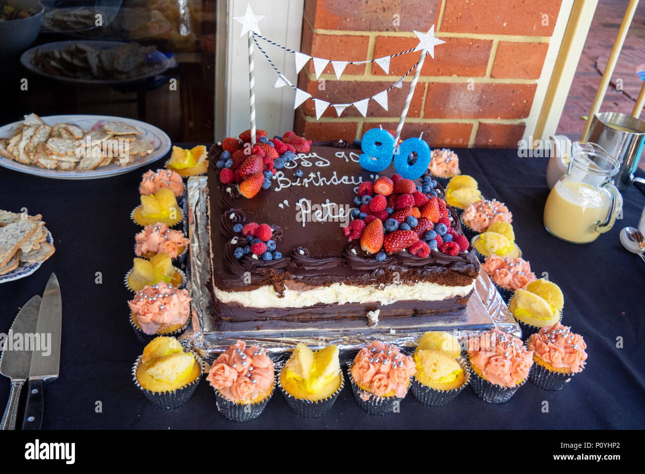 Una torta al cioccolato circondato da tortine per celebrare il novantesimo compleanno. Foto Stock