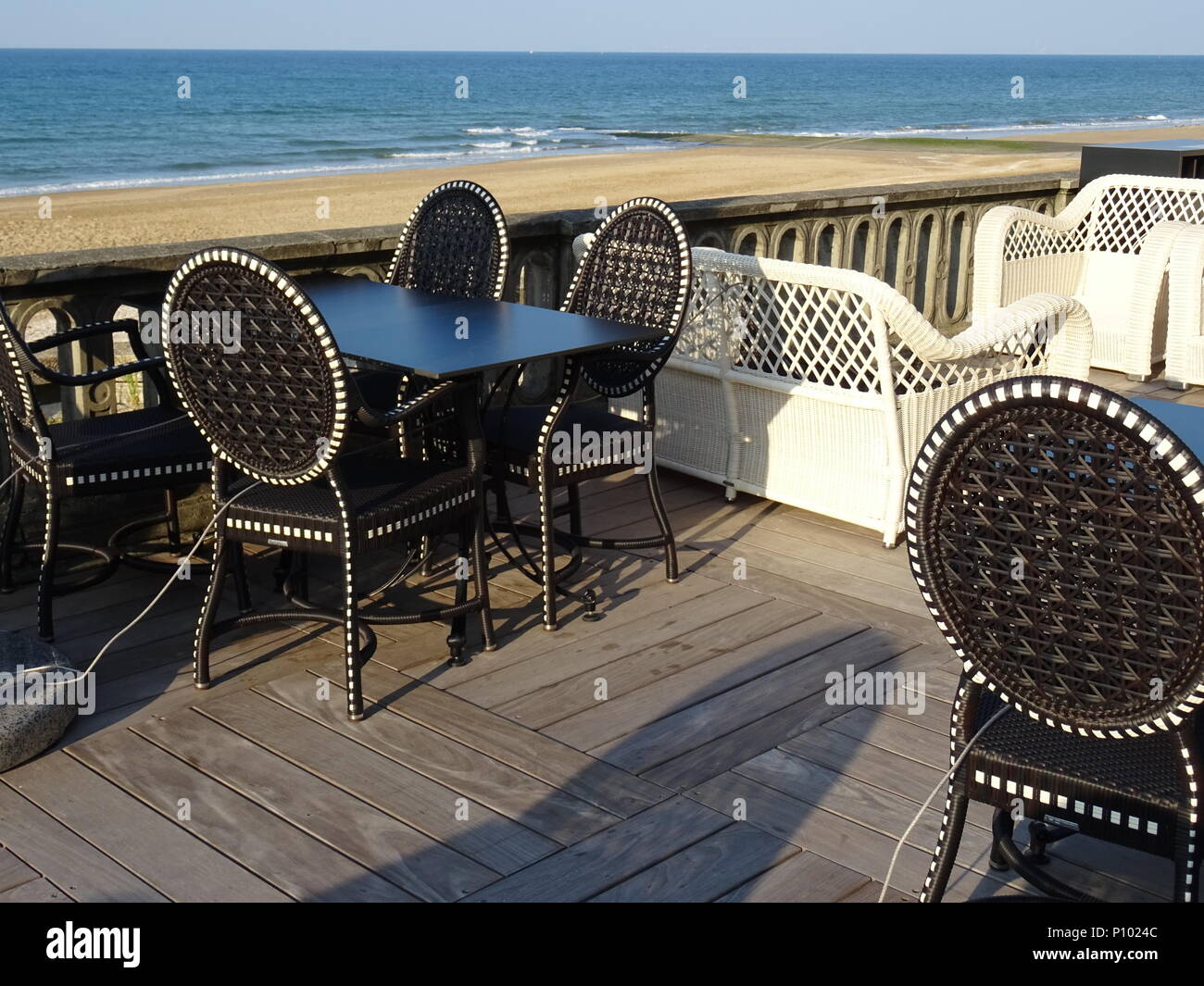 Bianco e nero sedie a sdraio, lettino e i tavoli di un caffè sulla spiaggia in Normandia, Francia con vista oceano Foto Stock