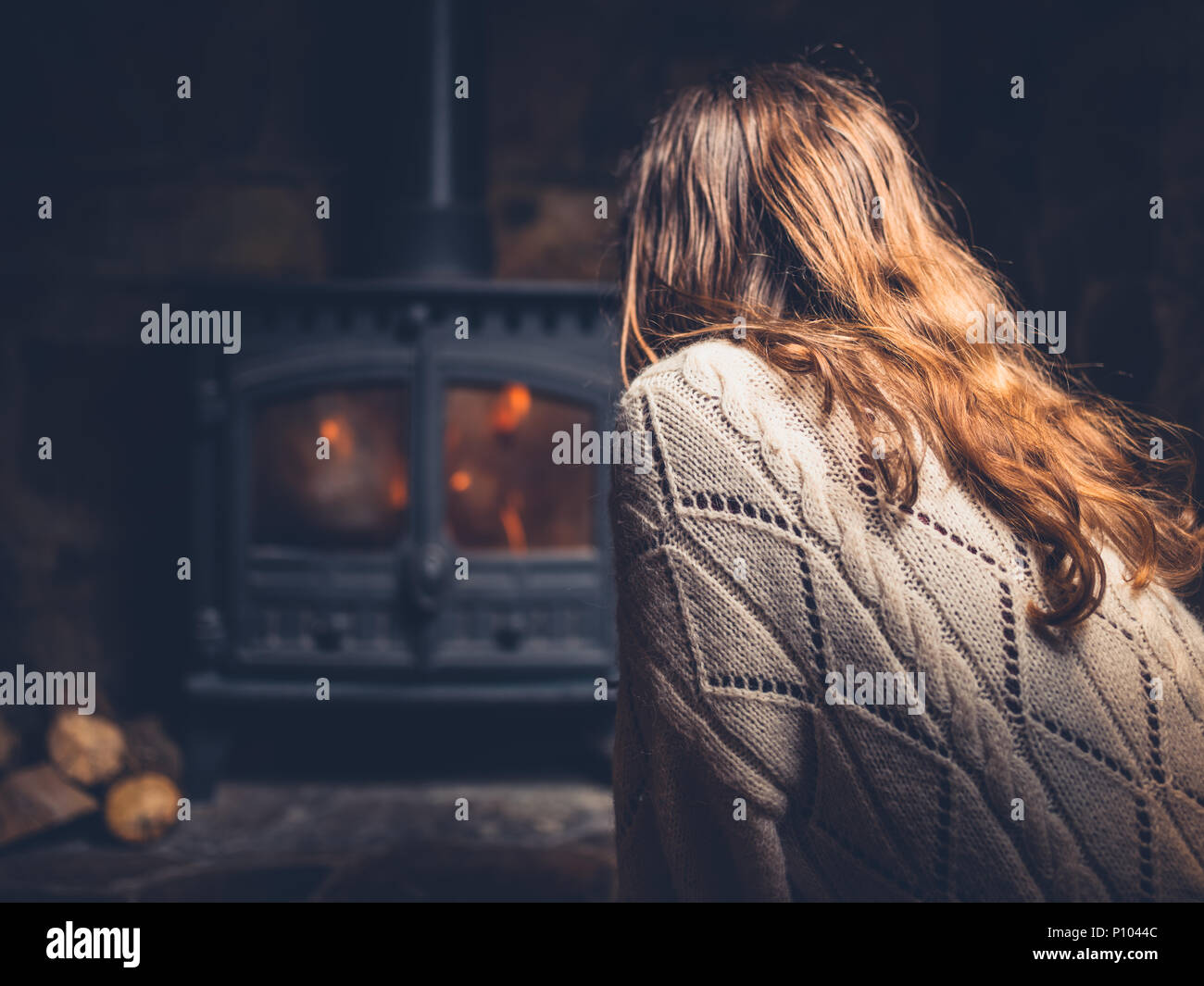 Una giovane donna si riscaldino dal fuoco di un bruciatore di registro Foto Stock