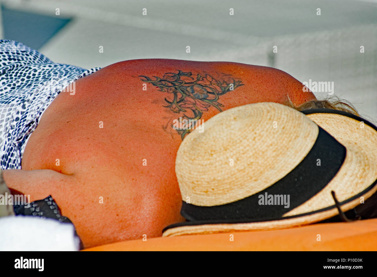 Donna con tatuato retro a prendere il sole. Foto Stock