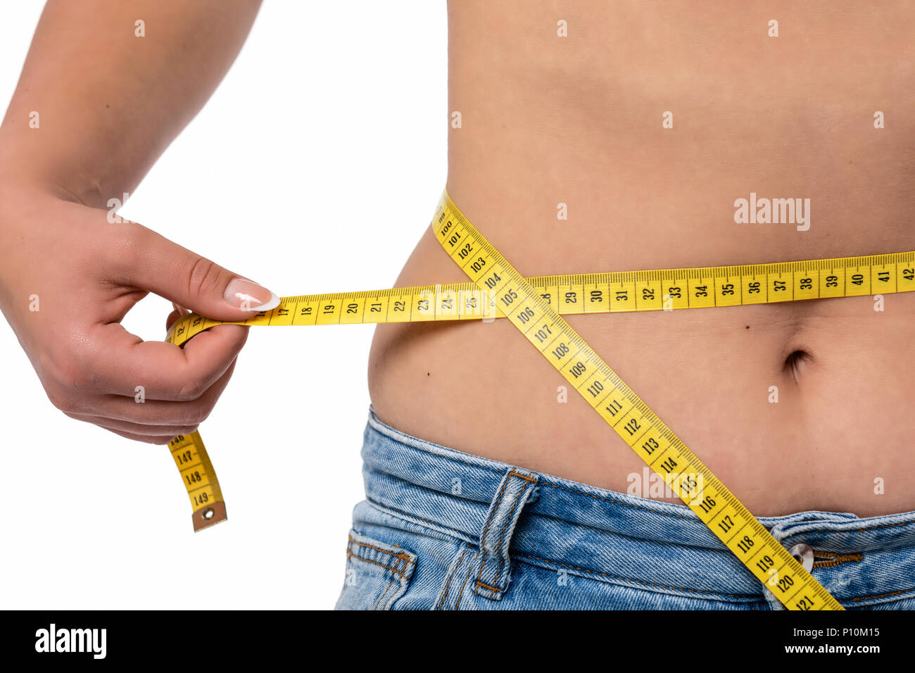 Uno stile di vita sano concetto - donna in jeans blu misura la sua girovita con un nastro di misurazione in close-up Foto Stock