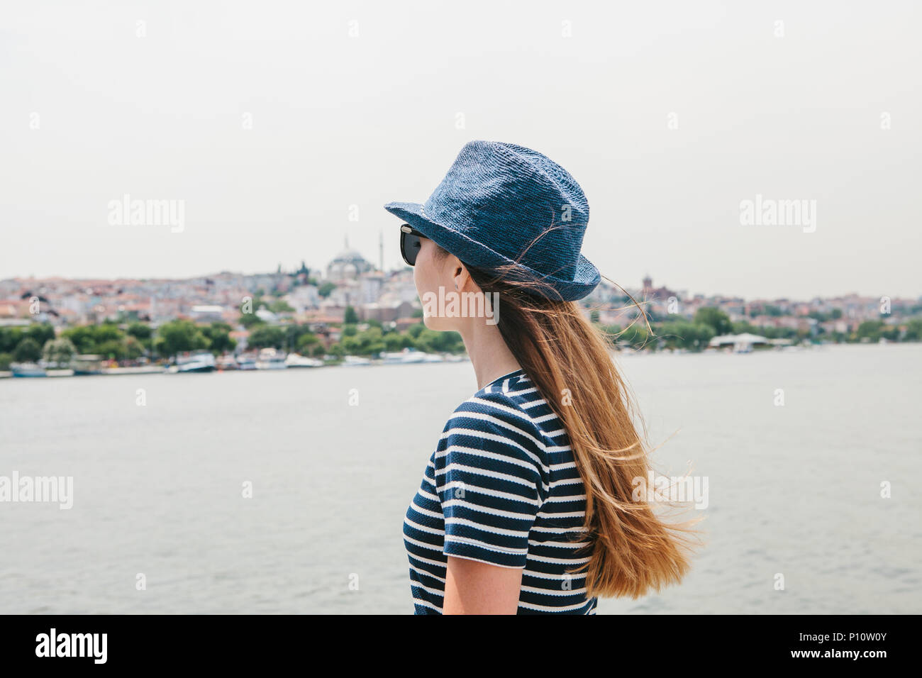 Una giovane bella ragazza in un cappello è quello di trascorrere una vacanza in Turchia e belle vedute del Bosforo e Istanbul in distanza Foto Stock