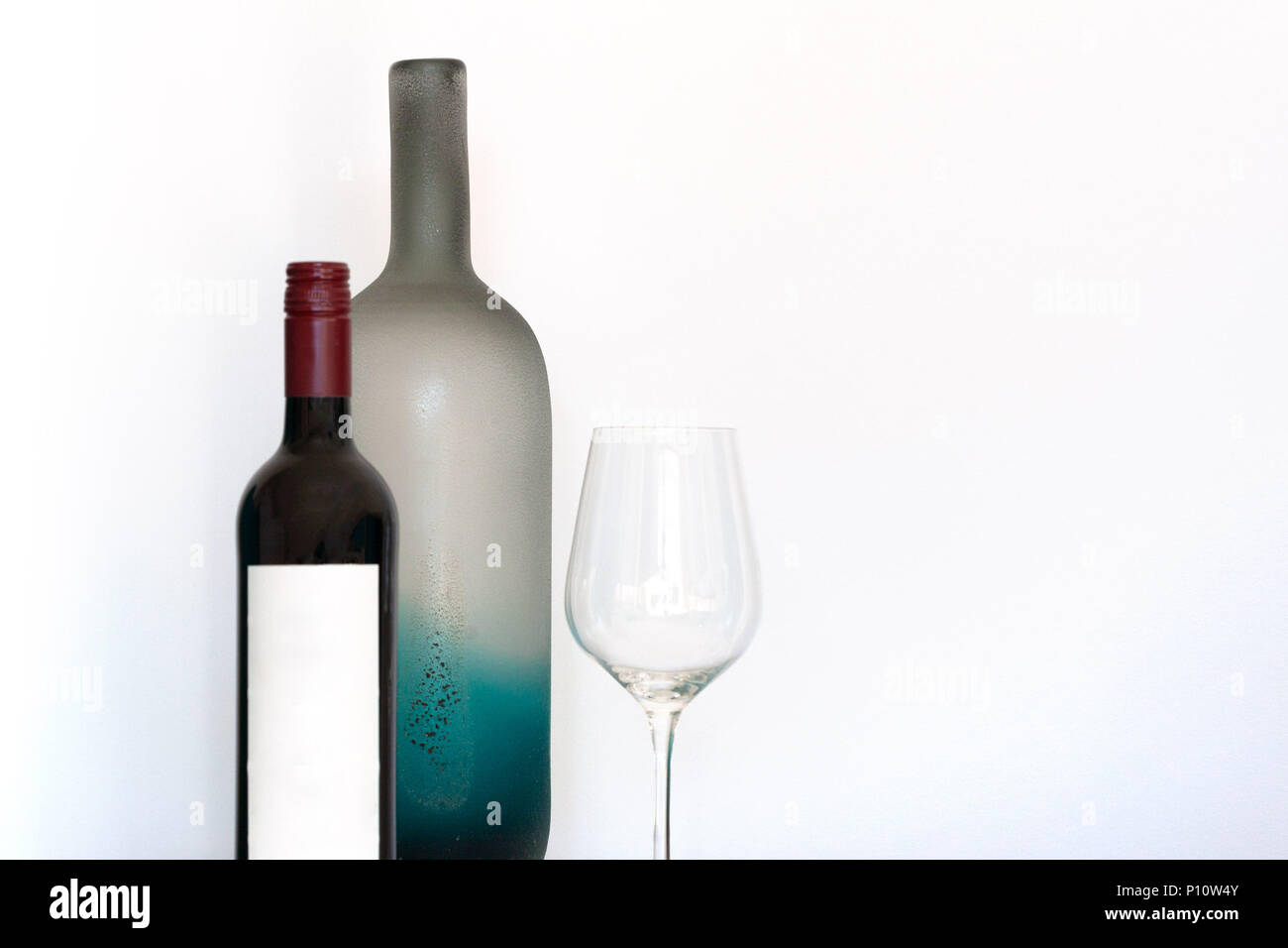 Bottiglia di vino con etichetta vuota, wineglass e di elementi decorativi in vetro smerigliato bottiglia su sfondo bianco con spazio di copia Foto Stock