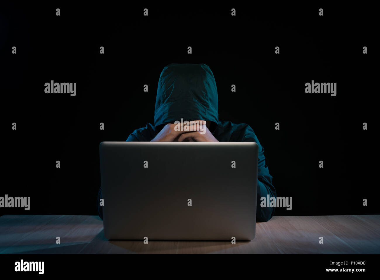 Hacker in una felpa con cappuccio scuro seduto davanti a un notebook. Calcolatore attacco sulla privacy Foto Stock