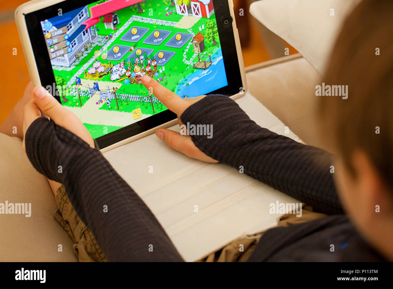 Riproduzione di giochi di allevamento su un tablet iPad Foto Stock