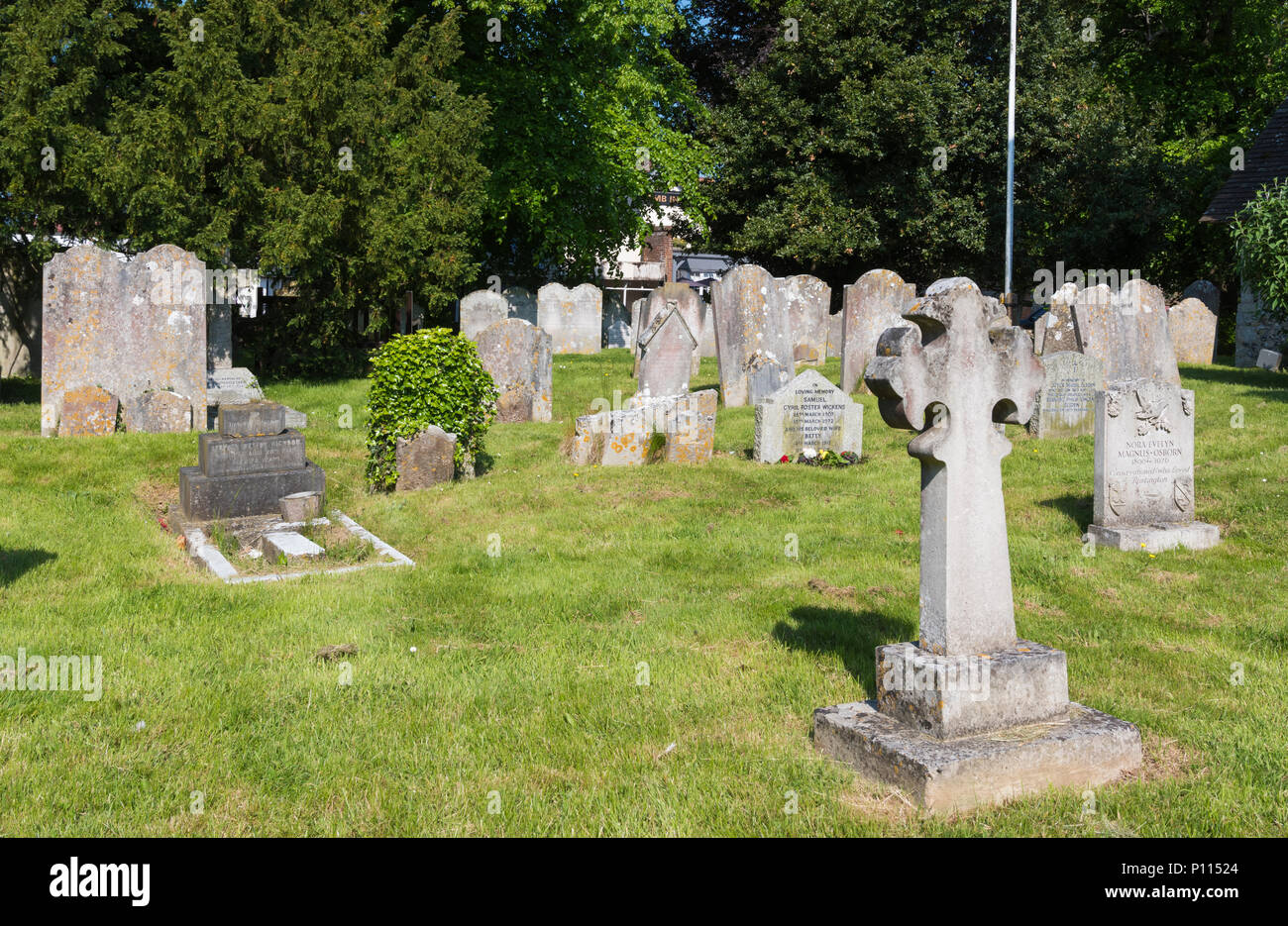 Piccolo cimitero o cimitero con vecchie lapidi su ben kempt erba tagliata a San Pietro e San Paolo Chiesa in Rustington, West Sussex, in Inghilterra, Regno Unito. Foto Stock