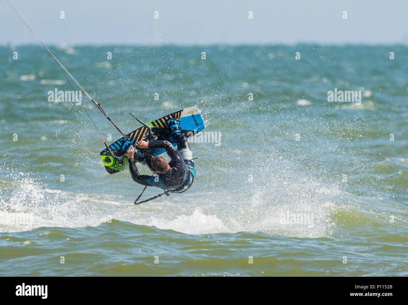 Extreme sport d'acqua come un uomo di kitesurf vola capovolto in aria come parte di uno stunt in mare, nel Regno Unito. Foto Stock