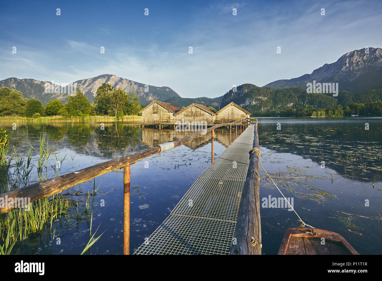 Vista del lago Kochelsee con boathouses di legno contro la gamma della montagna - Baviera, Germania Foto Stock