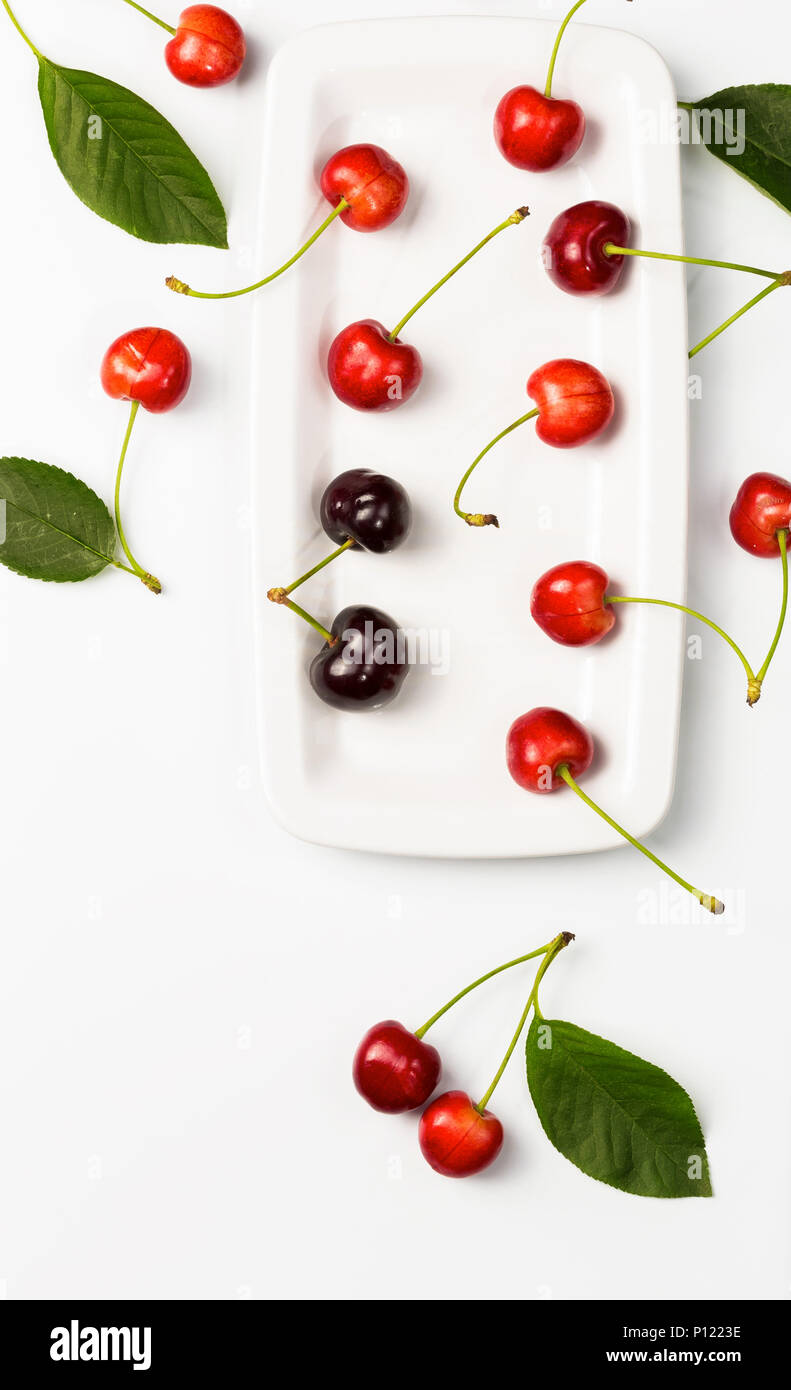 La ciliegia di bacche e foglie di ciliegio su sfondo bianco con spazio per il testo. Vista dall'alto. Sfondo alimentare presentazione campione. Foto Stock