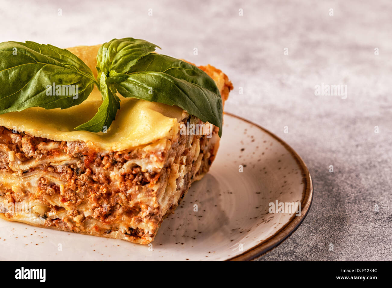Lasagne tradizionali realizzati con le carni bovine macinate ragù alla bolognese e besciamella guarnita con foglie di basilico. Foto Stock