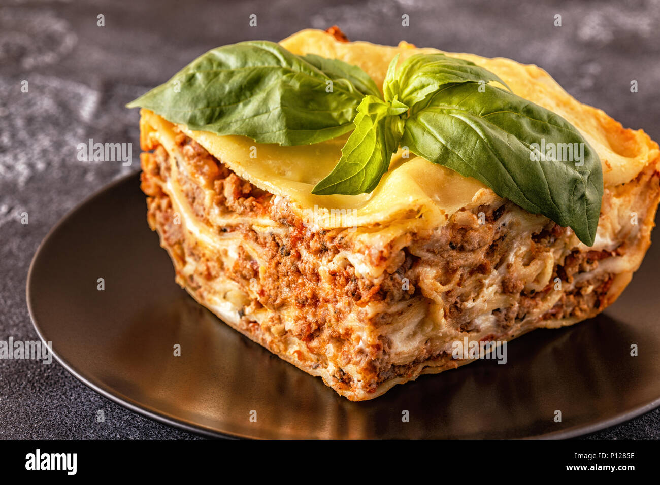 Lasagne tradizionali realizzati con le carni bovine macinate ragù alla bolognese e besciamella guarnita con foglie di basilico. Foto Stock