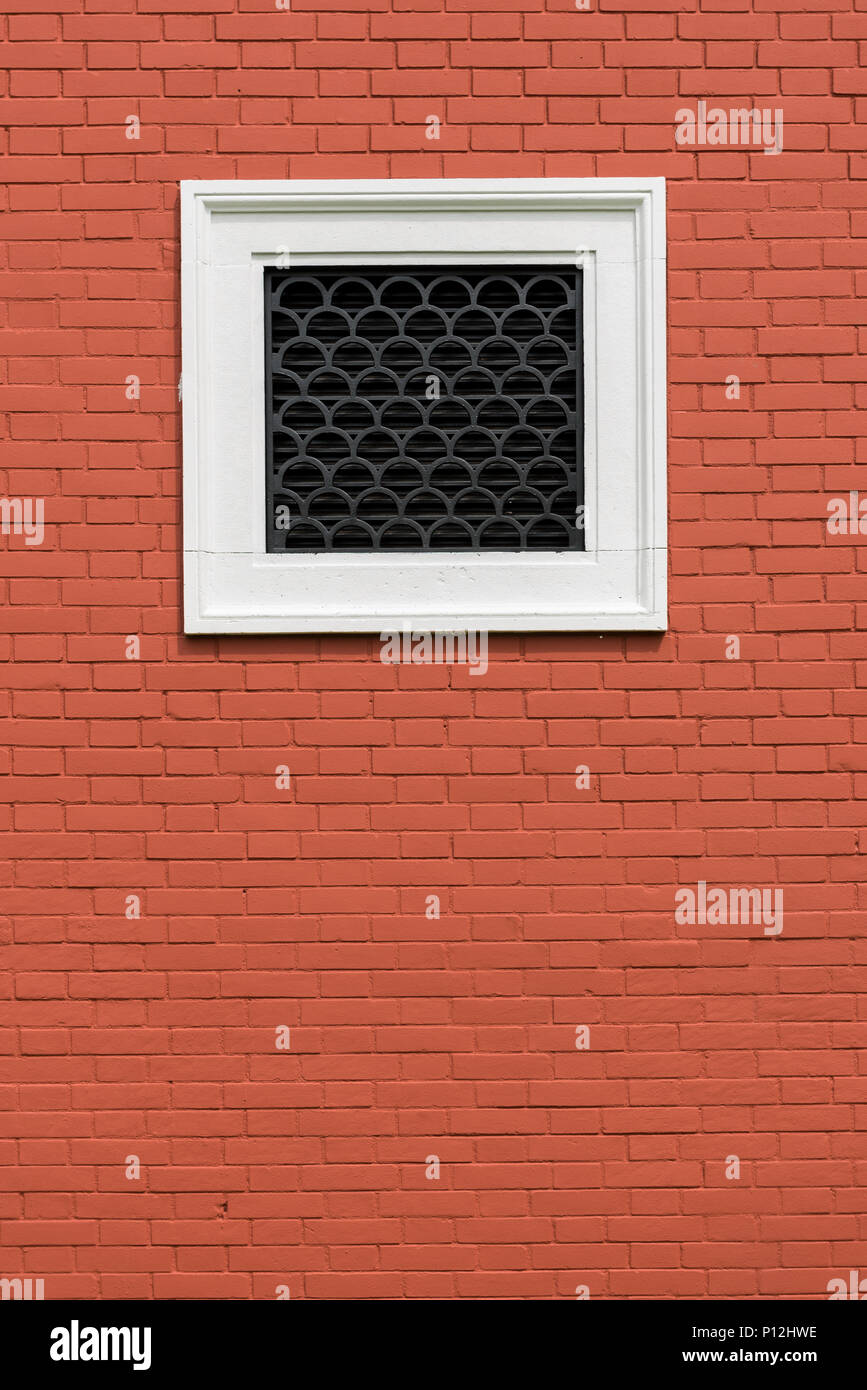 Rosso forte muro di mattoni con finestra bianca in mezzo. Rosso, arancione piastrelle Foto Stock