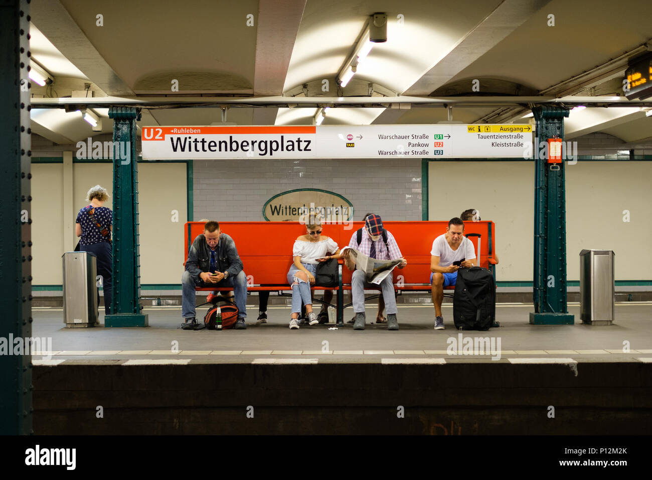 Berlino, Germania - giugno , 2018: Gente seduta sul banco slooking al telefono cellulare mentre si è in attesa per il treno della metropolitana presso la stazione Wittenbergplatz a Berlino, Foto Stock