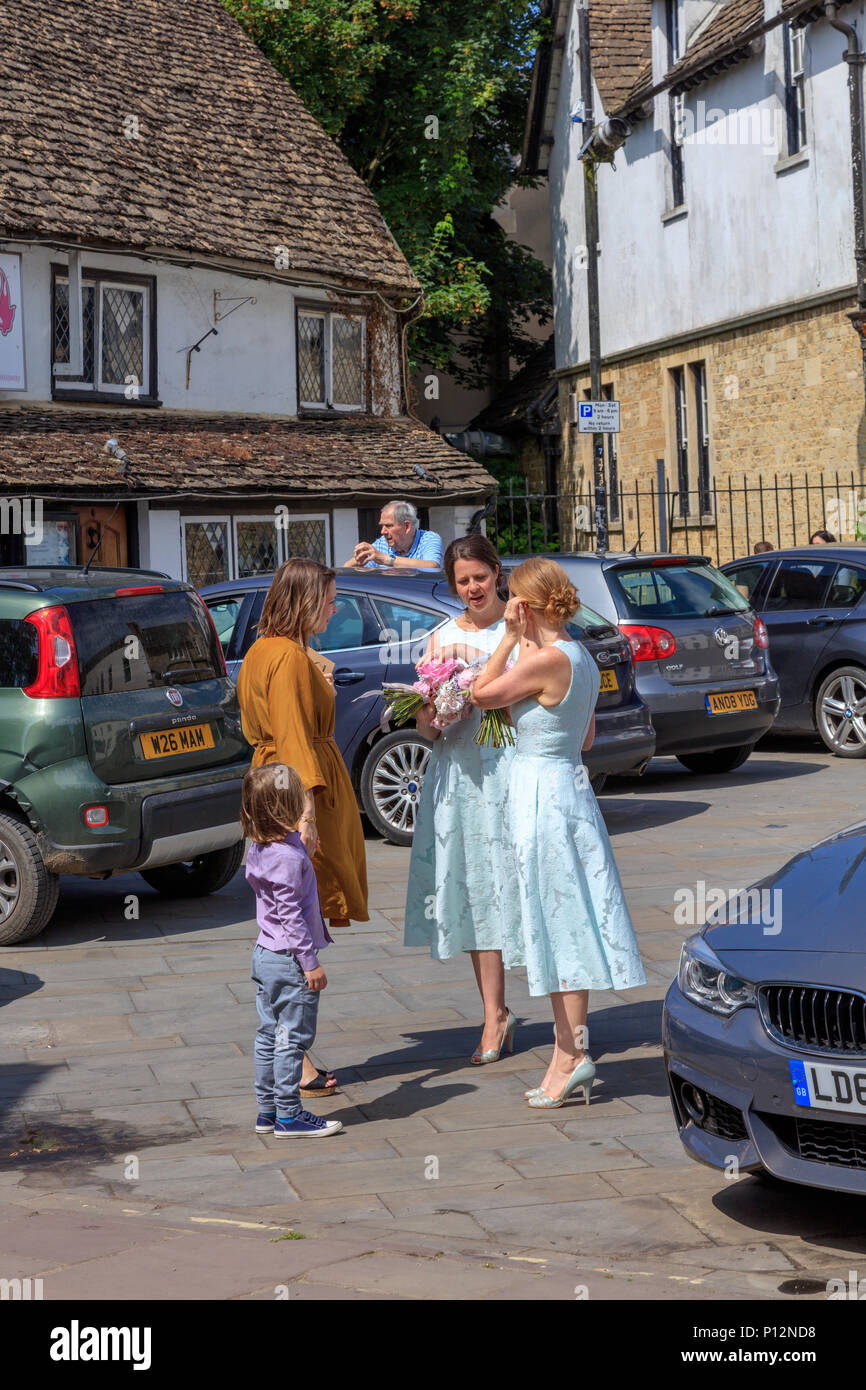 Gli ospiti dei matrimoni e damigelle in piazza del mercato dopo un matrimonio in Malmesbury Abbey, Wiltshire, Regno Unito Foto Stock