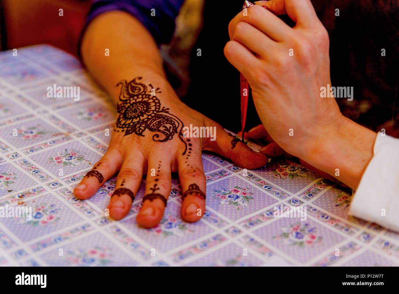 Donna artista mehendi pittura henna sulla mano. Foto Stock