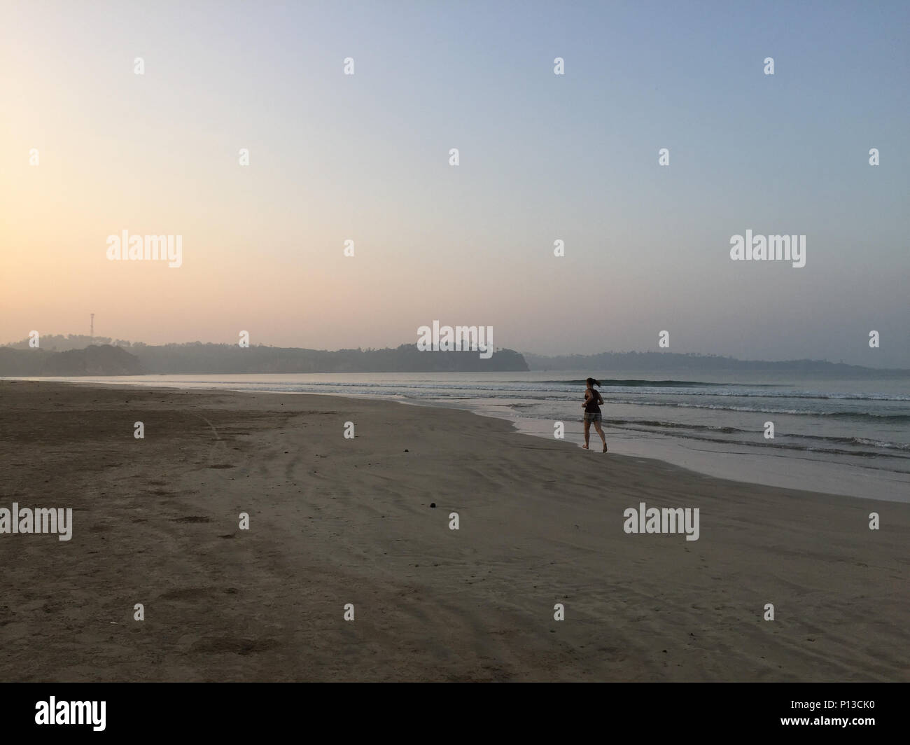 Un giovane turista è jogging sulla spiaggia durante il sunrise a Weligama Bay, Sri Lanka Foto Stock