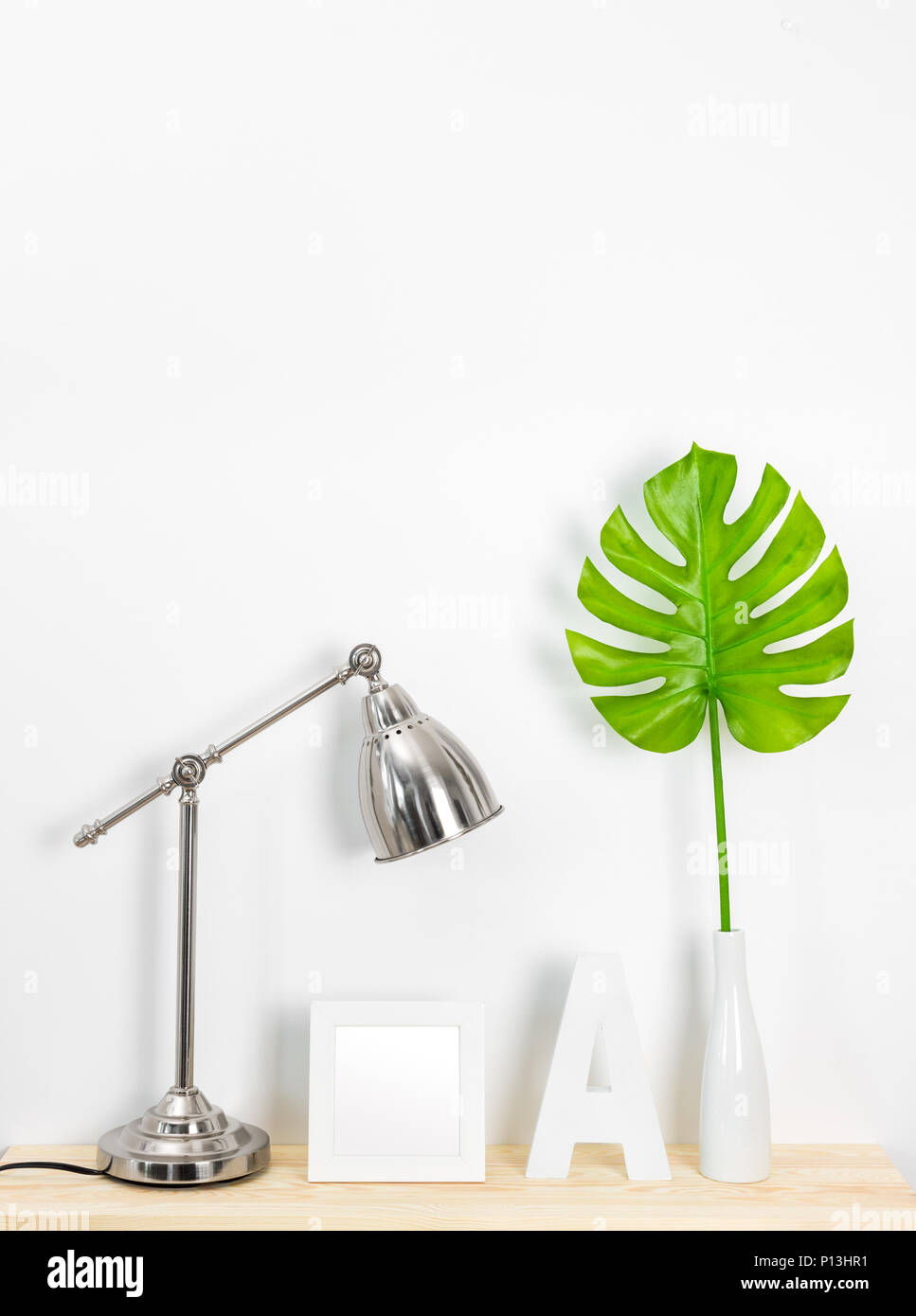 Elegante arredamento di casa con lampada in metallo, picture frame, lettera A e foglia tropicale. Ispirato dal design scandinavo. Foto Stock