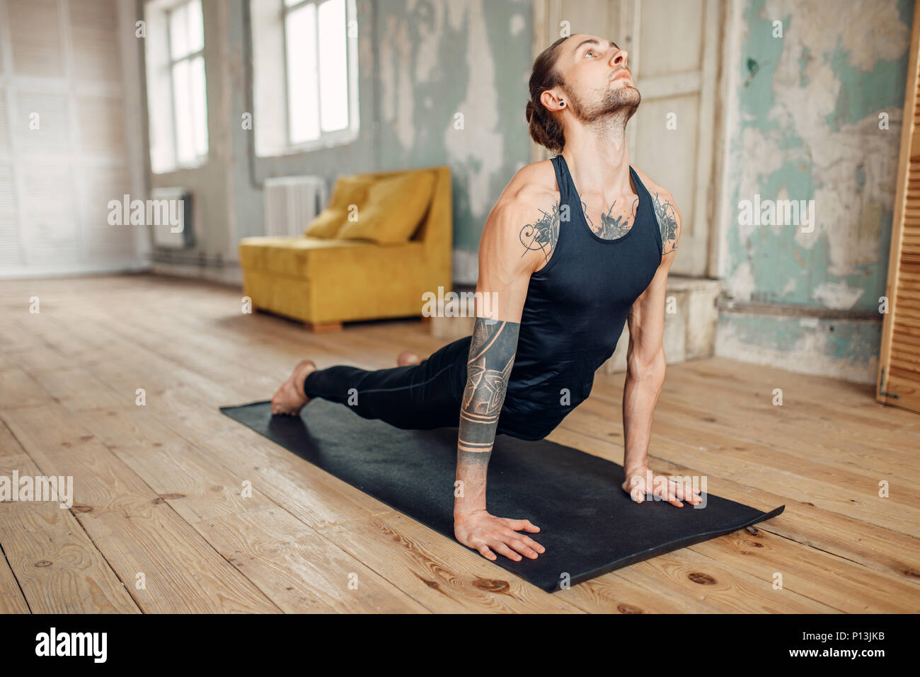 Yoga maschio con tatuaggio sul lato facendo spingere verso l'alto esercizio in palestra con grunge interni. Allenamento fitness in ambienti interni Foto Stock