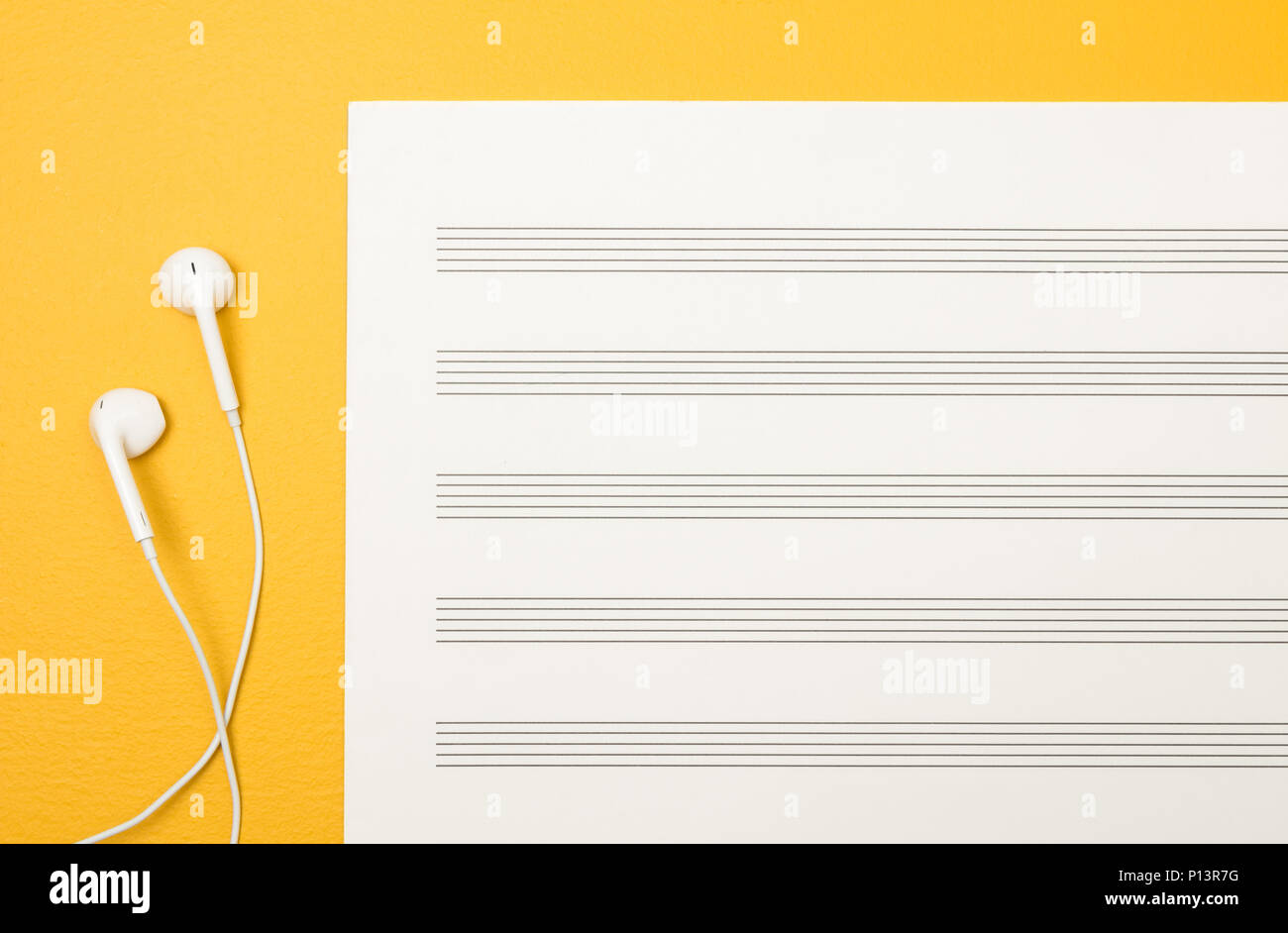 Gli auricolari bianchi e musica vuota il foglio di carta sul vivace sfondo giallo. Foto Stock