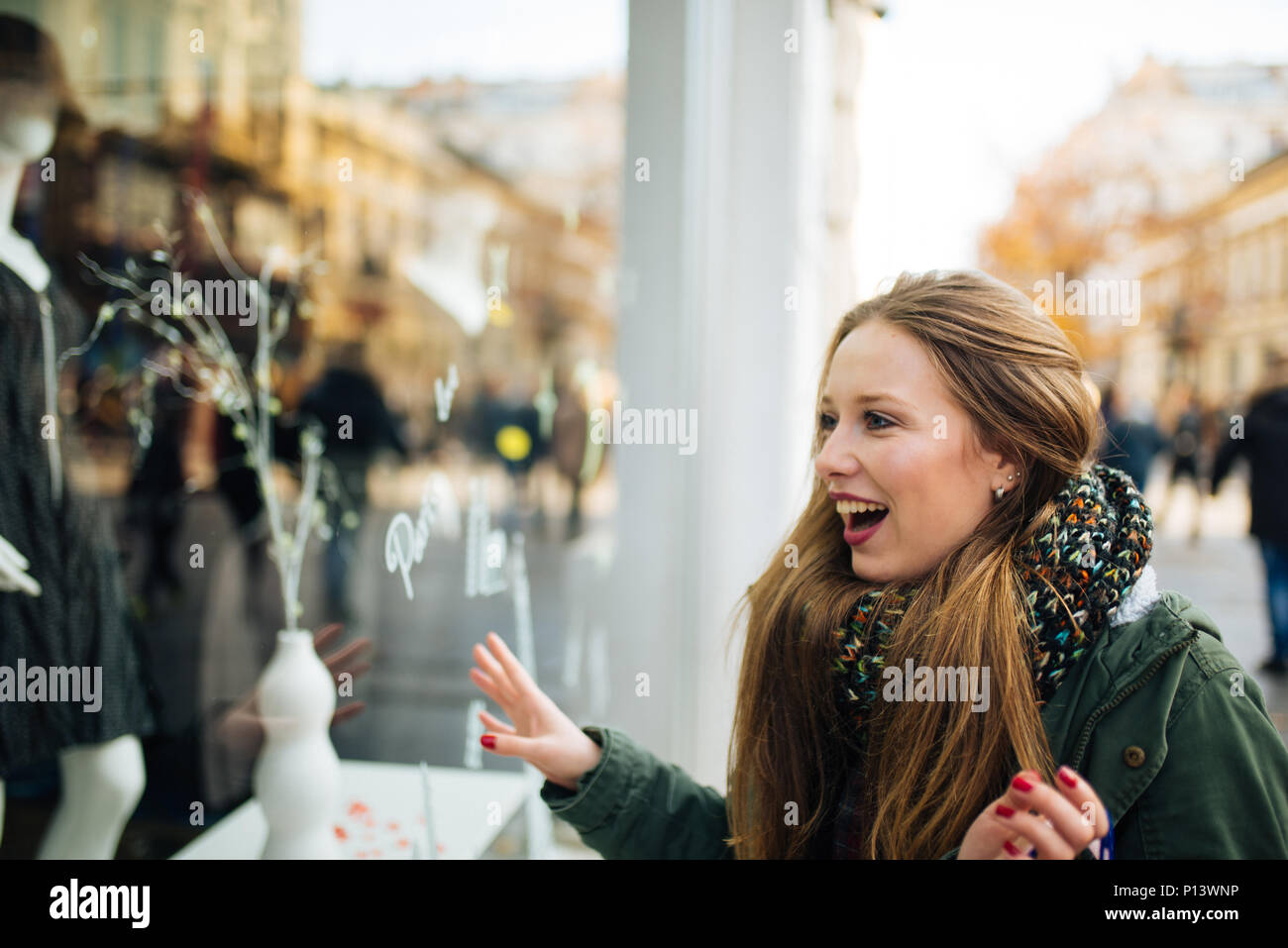 Attraente giovani dai capelli lunghi donna è eccitato nella parte anteriore della finestra commerciale Foto Stock