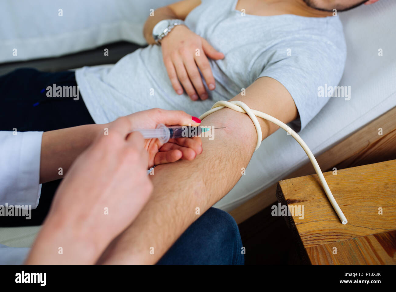 Medico donna prendendo un sangue dal paziente di sesso maschile nella clinica privata Foto Stock