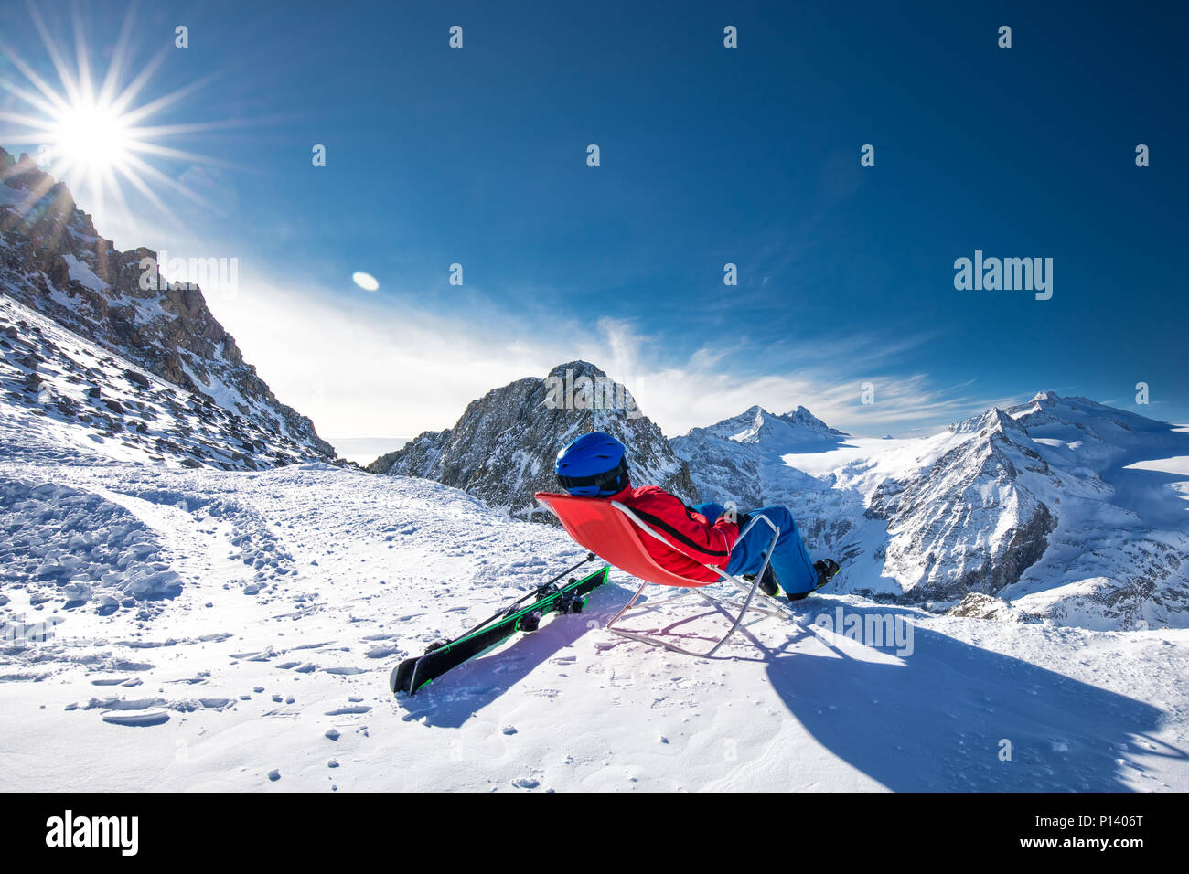 Giovane sciatore happtyattractive seduto sulla cima delle montagne godendo la vista dal ghiacciaio Presena, Tonale, Italia. Foto Stock