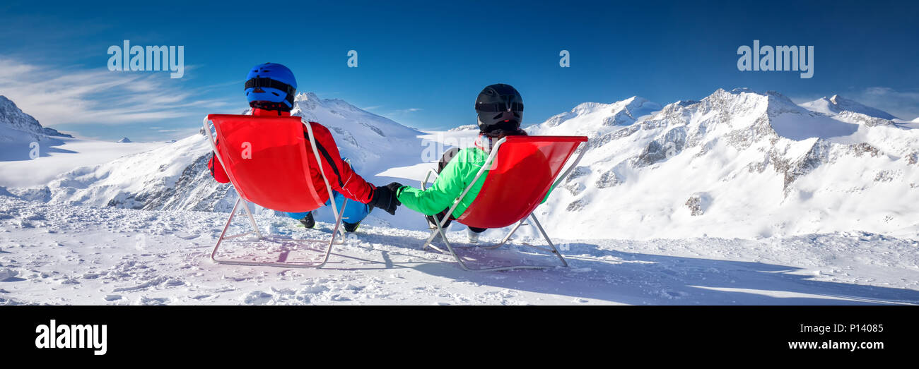Coppia giovane seduti su sedie a sdraio e godersi la splendida vista delle Alpi, l'Europa. Foto Stock