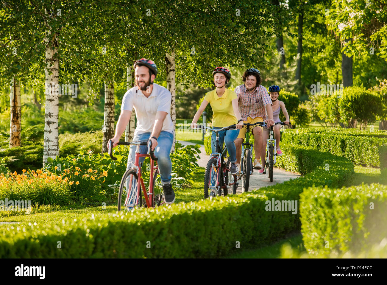 Happy amici in bicicletta nel parco della città. Gruppo di studenti equitazione biciclette in estate La natura dello sfondo. Persone e riposo attivo. Foto Stock