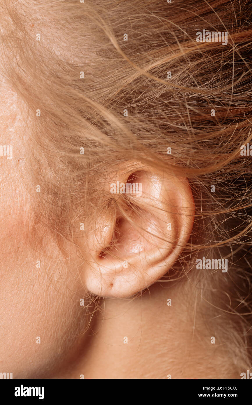 Dettaglio della testa femmina con un orecchio umano e capelli biondi close up. Foto Stock