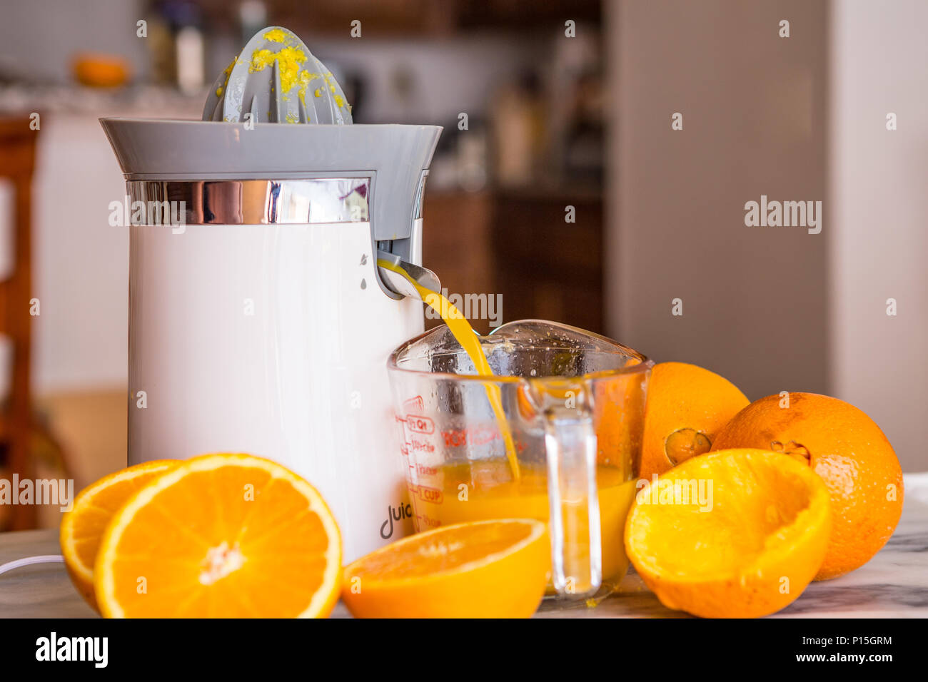 Il piano portapaziente arancione elettrico e spremitura di agrumi in una  cucina domestica con fresco intero e tagliare le arance Foto stock - Alamy