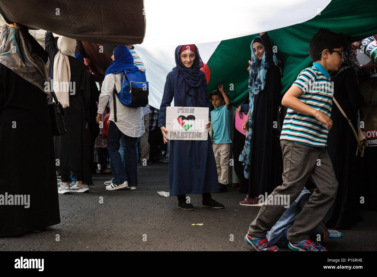 Londra, Regno Unito. Decimo Giugno, 2018. Una ragazza sta con un 'Free Palestine' firmare al di sotto di una gigantesca bandiera palestinese essendo mantenuto fino al di fuori dell'ambasciata saudita prima di centinaia di persone che prendono parte alla pro-palestinese Al Quds giorno marzo attraverso il centro di Londra organizzata dalla Commissione islamica per i diritti dell'uomo. Un evento internazionale, ha cominciato in Iran nel 1979. Quds è il nome arabo di Gerusalemme. Credito: Mark Kerrison/Alamy Live News Foto Stock