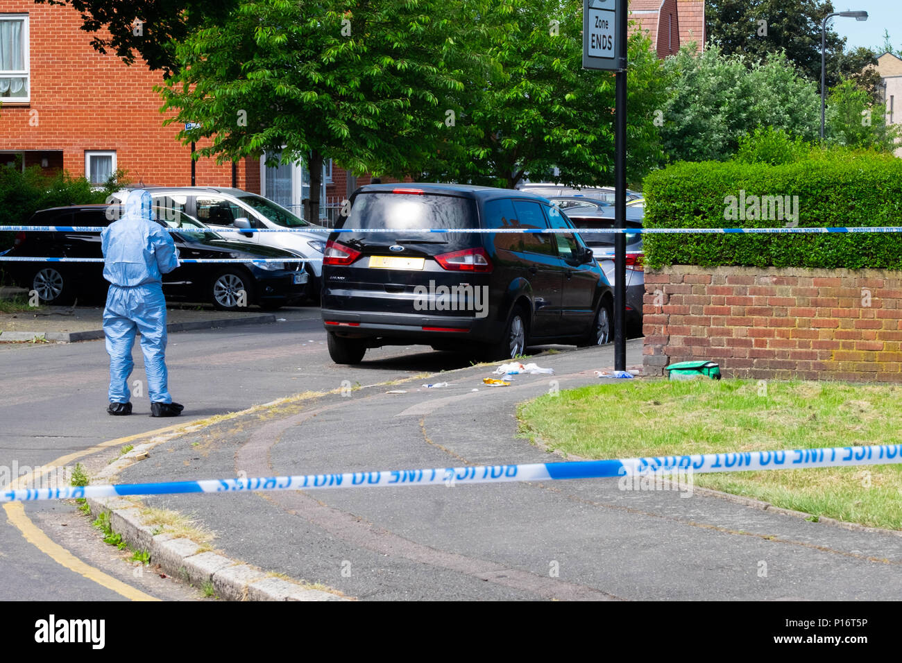 Londra, Inghilterra. 11 giugno 2018. La mattina dopo un altro adolescente è pugnalato a Londra, un funzionario forense controlla la scena del crimine per indizi entro una zona isolati da un cordone di polizia. Questo pugnalare accaduto appena un breve periodo di tempo dopo che un uomo è stato pugnalato a poche miglia di distanza in Northolt. ©Tim anello/Alamy Live News Foto Stock