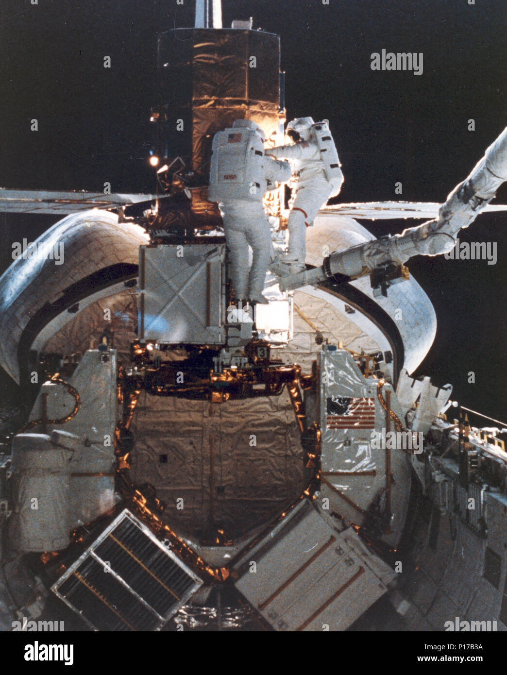 STS-41c astronauti D. George Nelson, destra e James D. van Hoften condividono un compito di riparazione al catturato massimo solare missione satellitare (SMMS) nell'estremità di poppa del Challenger cargo bay. I due lo specialista di missione utilizzare il piede mobile di ritenuta e il telecomando sistema di manipolatore (RMS) come un 'cherry picker' dispositivo per la movimentazione di circa. In seguito, il valore RMS sollevato il SMMS nello spazio una volta di più. Foto Stock