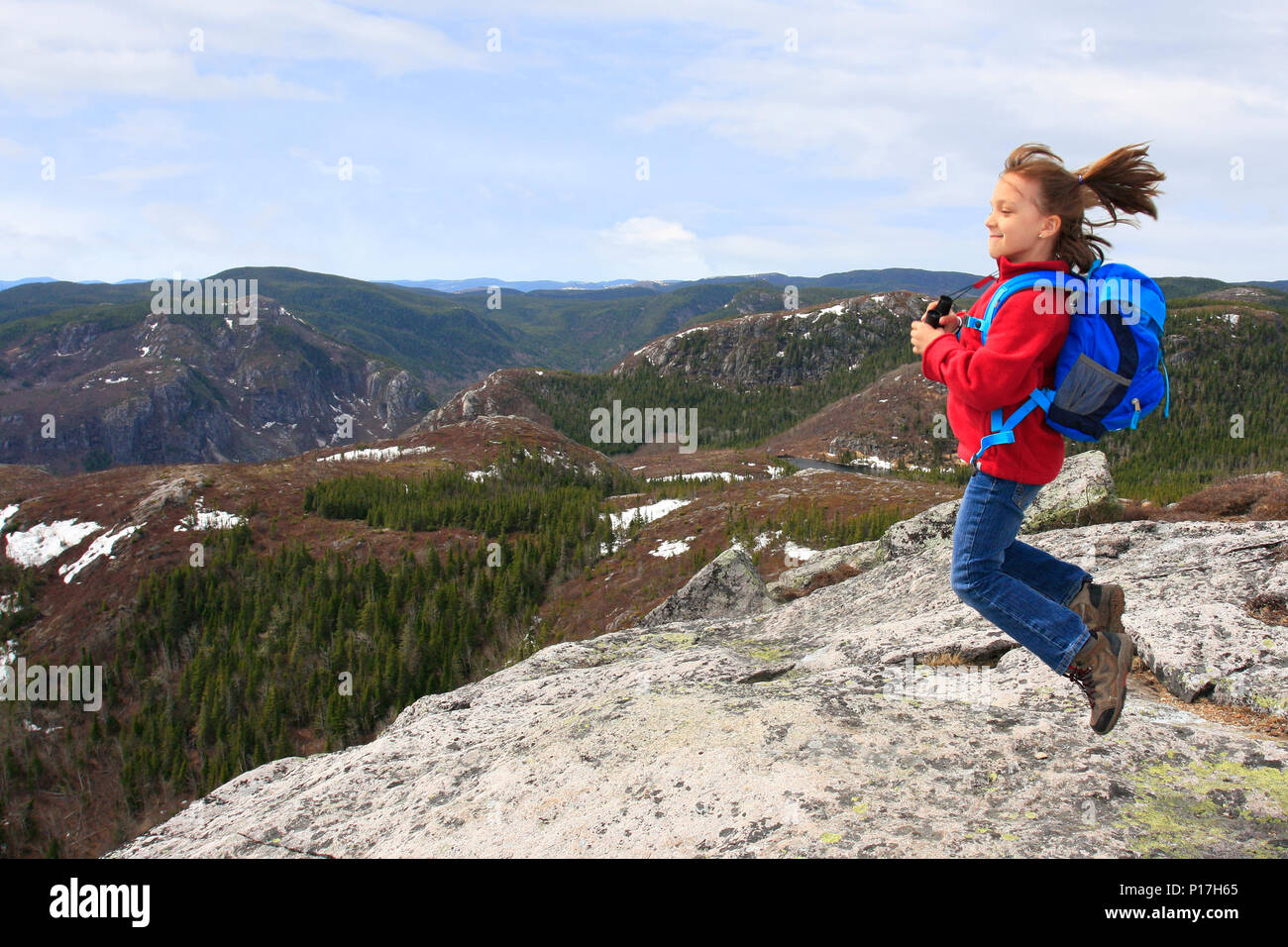 Ragazza escursionista jumping e ammirando la bellezza del paesaggio dalla vetta del Mont du Lac des Cygnes nel Parc National des Grands-Jardins, Quebec, Foto Stock