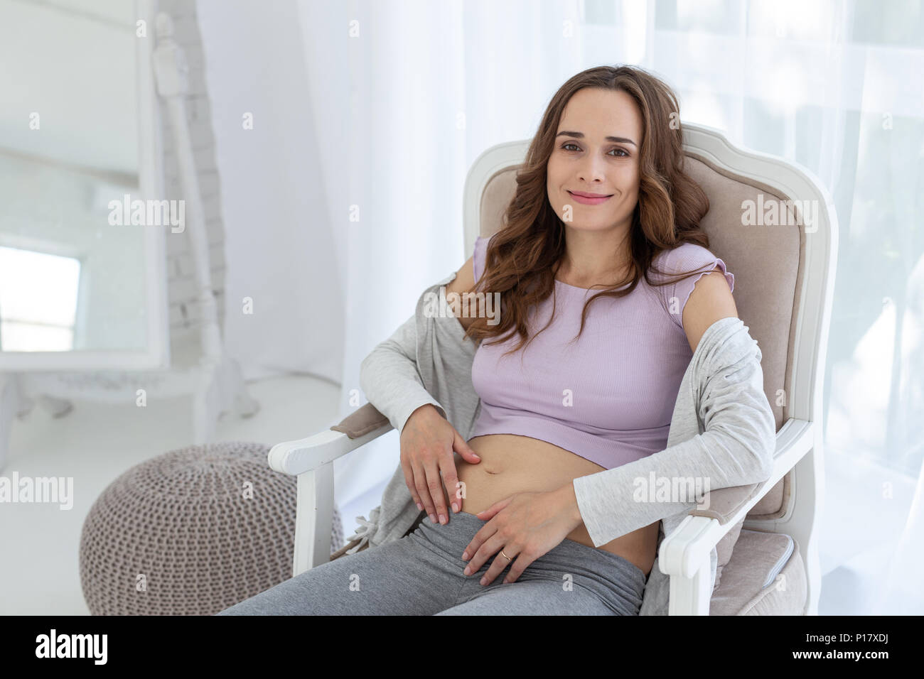 Allegra donna incinta in appoggio su una sedia Foto Stock