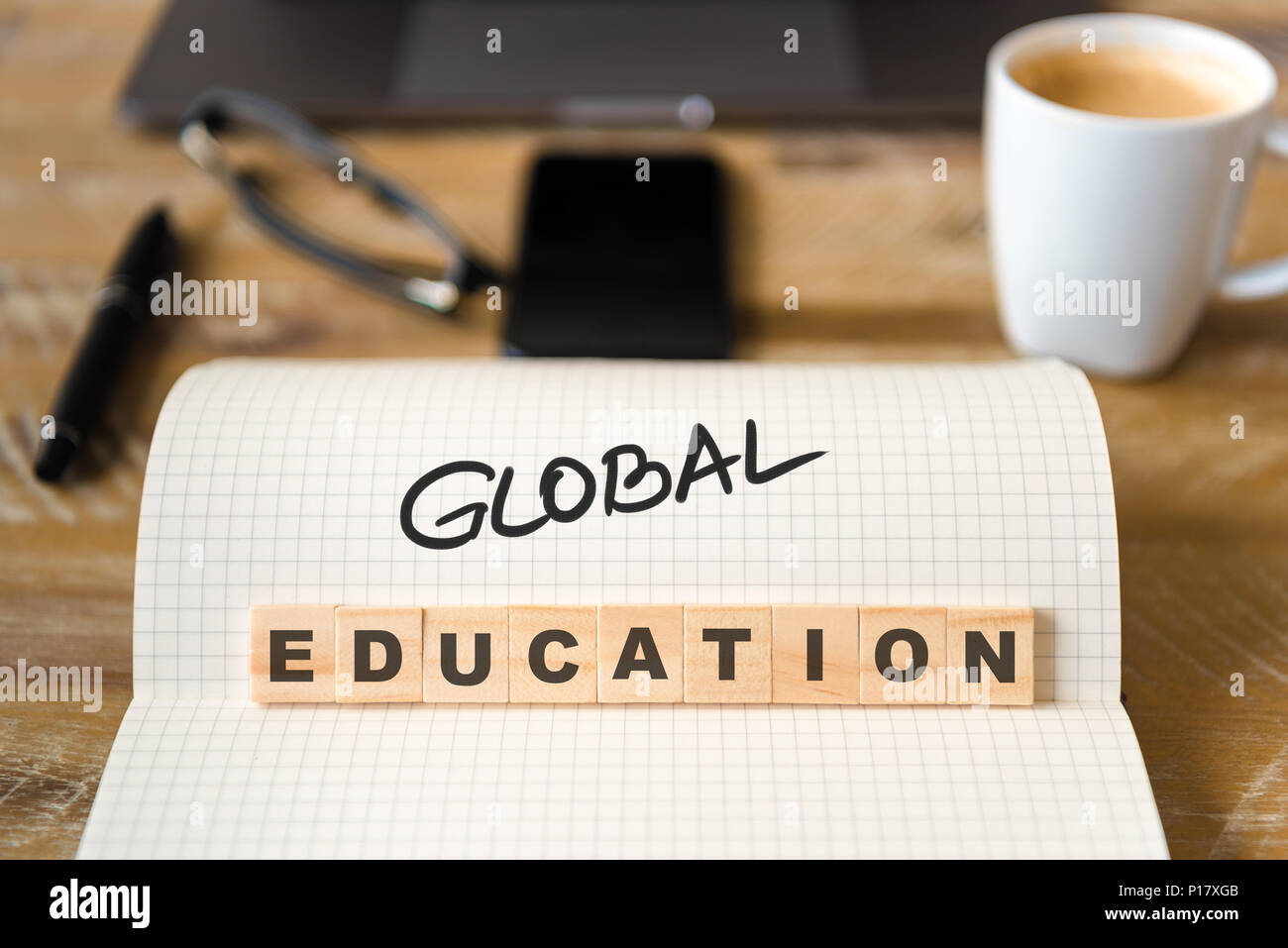 Primo piano su notebook sulla scrivania vintage superficie, di fronte a fuoco sui blocchi di legno con lettere che l'istruzione globale del testo. Foto Stock