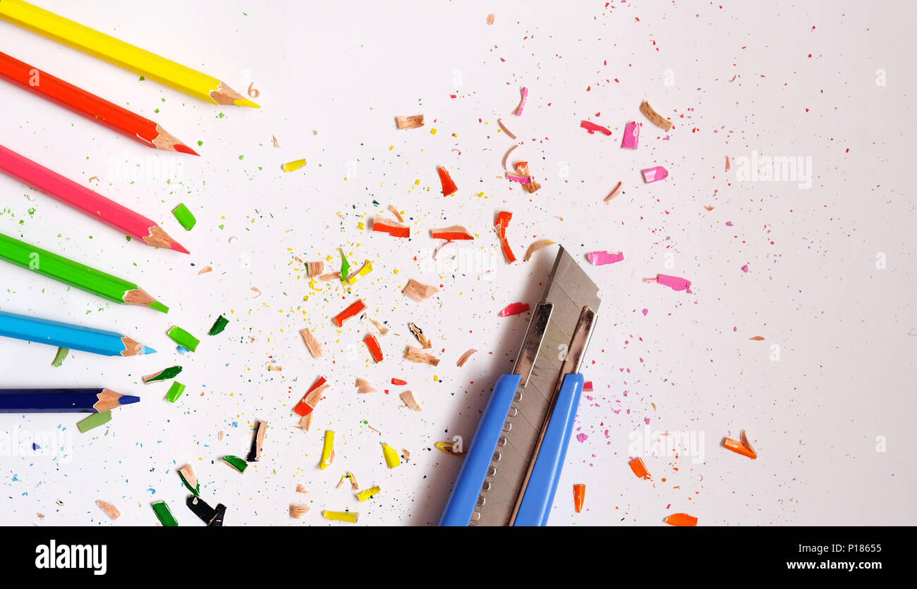 Piatto di laici sei matite di colore e una blu coltello, con matita colorata trucioli sparsi intorno. Foto Stock