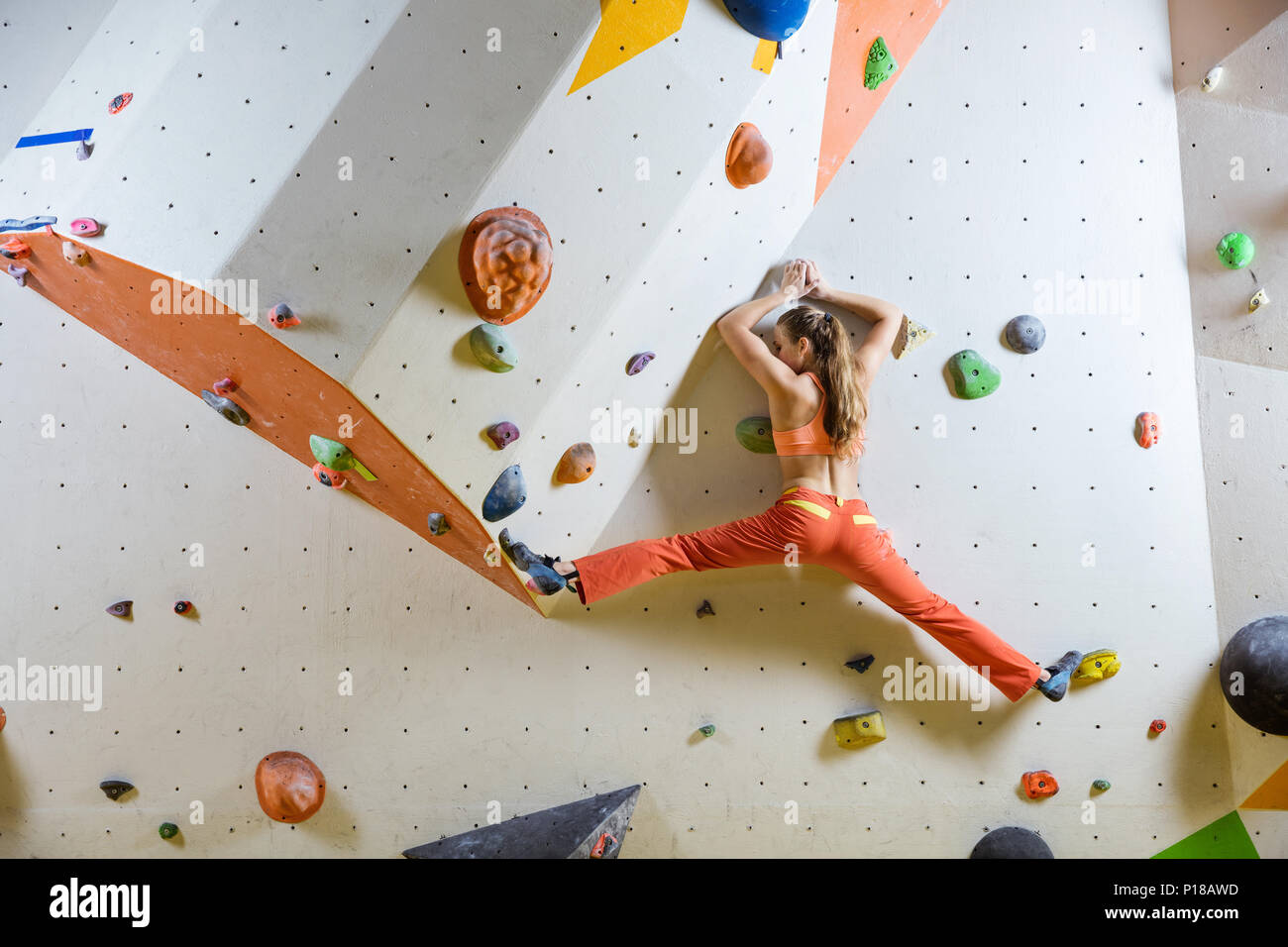Giovane donna di arrampicata bouldering impegnativo percorso Foto Stock