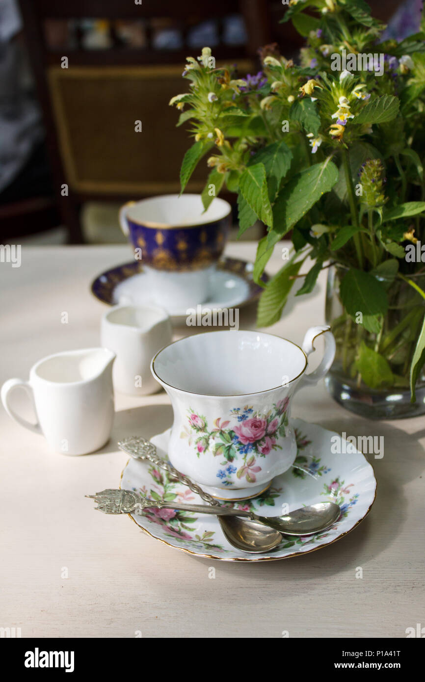 Vintage Tazza in porcellana, argento cucchiaio da tè e bouquet di fiori di campo estivo su un tavolo. Il relax accogliente casa vecchia campagna atmosfera rétro. Foto Stock