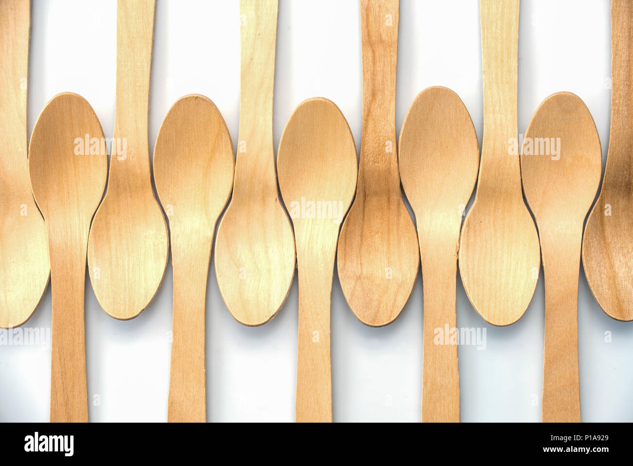Biodegradabile in legno cucchiai allineati su sfondo bianco Foto Stock