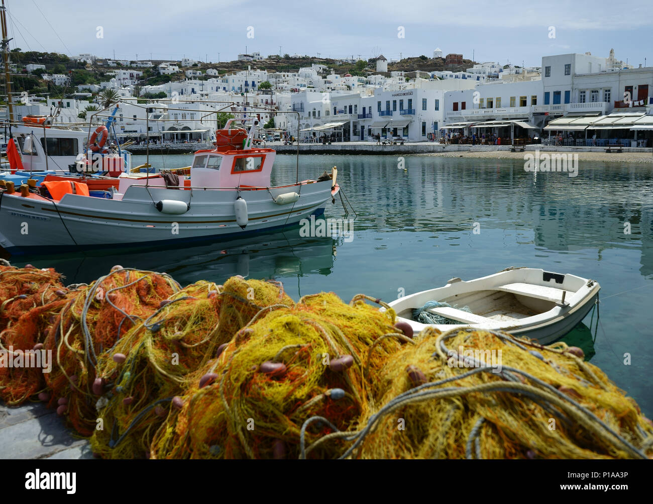 Barche da pesca e reti in porto con abitato Mykonos, Cicladi,, Grecia Foto Stock