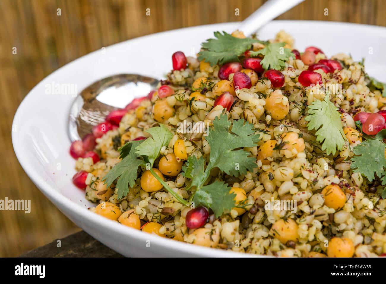 Ceci, bulgar di frumento e di orzo perlato pilaf con melagrane e coriandolo, servita all'aperto. Foto Stock