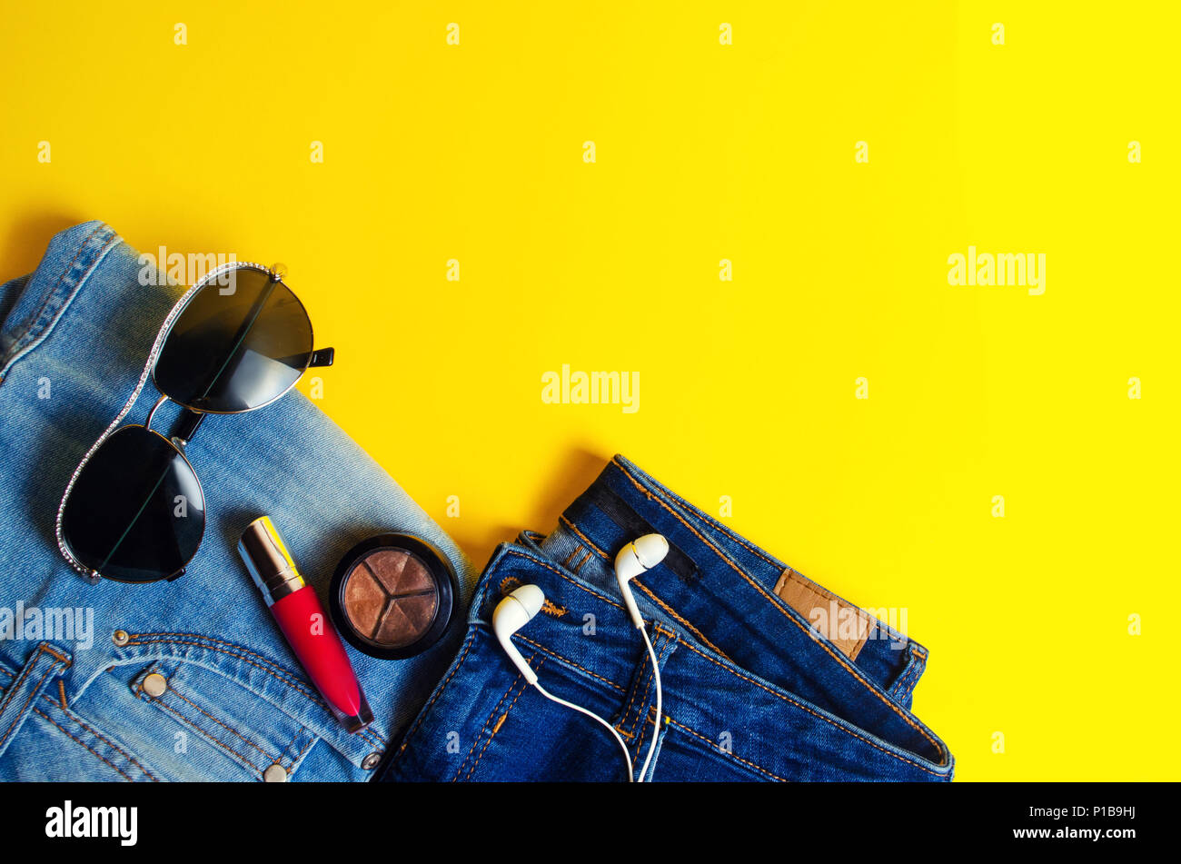 Donna di cose, accessori eleganti . Jeans, rossetto, bicchieri, cuffie. luogo di testo. sfondo giallo. estate. concetto di moda, stile di vita, Foto Stock