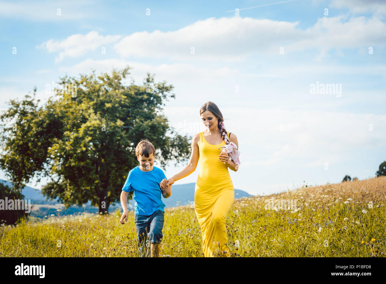 Madre con suo figlio in esecuzione su un prato estivo Foto Stock