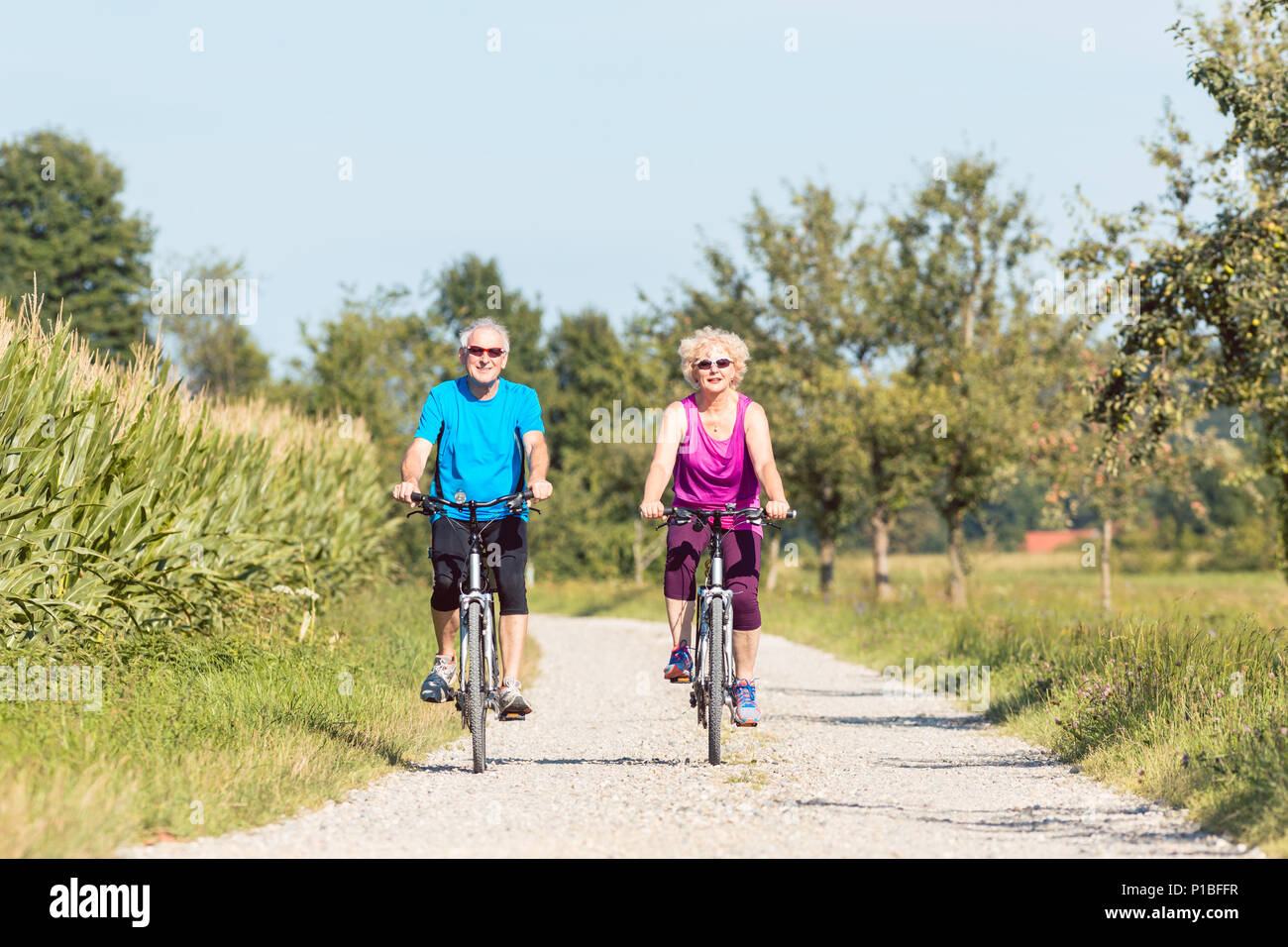 Attivo coppia senior godendo il pensionamento mentre in bicicletta nel parco Foto Stock